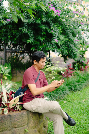 A cheerful man sits at an outdoor villa, looking excited as he enjoys the relaxing atmosphere and...
