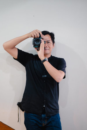 A male photographer, absorbed in his craft, focuses his camera, creating a portrait against a...