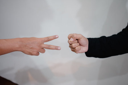 Two hands perform the classic rock, paper, scissors gesture against a plain backdrop. The image captures the essence of this well-known hand game, highlighting elements of decision-making andの写真素材
