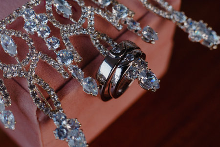 Close-up of two wedding rings and a diamond necklace, representing love and commitment, captured in intricate detail, highlighting the beauty of the jewelry, ideal for romantic concepts and specialの写真素材