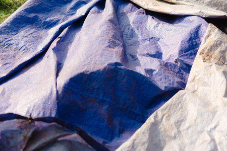An interesting close-up captures a wrinkled tarp with compelling textures. The blue and white hues create a dynamic interplay of light and shadow, making it perfect for abstract backgrounds andの写真素材