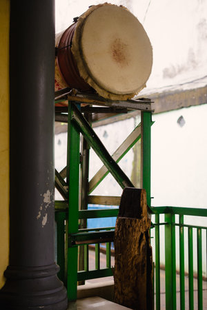 A traditional drum rests on a green wooden structure. The drum, with its aged appearance, suggests a history of use and cultural significance. The shot provides a glimpse into local traditionsの写真素材