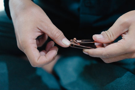 A close-up shot reveals a person's hands meticulously using a nail clipper, emphasizing the care taken for personal grooming and nail hygiene, the photo's focus is on the detailed process of nailの写真素材