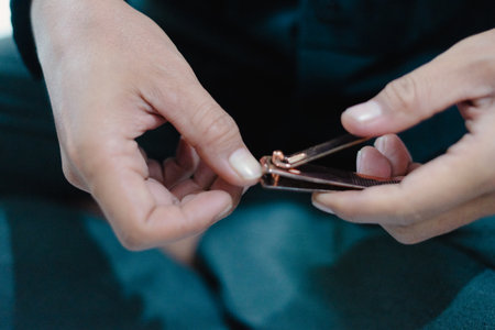 A close-up shot showing a person trimming their fingernails using a nail clipper. The image captures the detail of the hands, the nail clipper, and the act of personal grooming. The focus is on theの写真素材