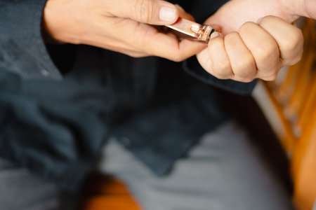 A close-up shot of a person's hand using nail clippers to trim their nails. This image captures the meticulous process of personal grooming, showcasing the precision and care involved in maintainingの写真素材