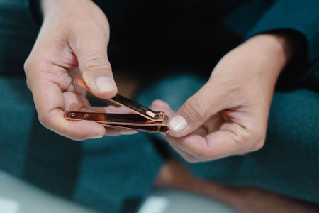 Close-up shot of a person trimming their nails with clippers. The image highlights the act of self-care, emphasizing personal hygiene and the use of a nail clipper for maintaining nail health andの写真素材