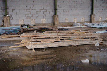 An interior shot of a construction site featuring a pile of wooden planks alongside other building...
