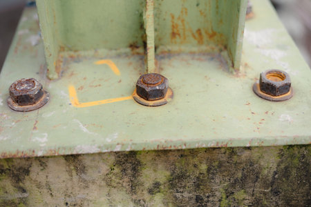 Close-up shot of three rusty bolts securing a metal structure. The green surface shows weathering, highlighting the industrial and aged nature of the components. The texture and detail demonstrateの写真素材