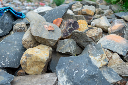 A close-up view of a diverse pile of natural rocks and stones, showcasing varied textures, earthy tones in an outdoor setting.の写真素材