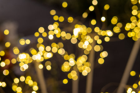 Abstract background featuring vibrant golden bokeh lights shimmering on a dark backdrop, perfect for festive celebrations, holiday designs, and greeting cards.の写真素材