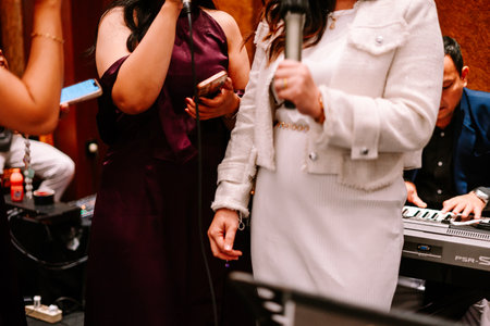 Guests participate in a fun karaoke session, singing their favorite songs with live musical accompaniment at a celebration.の写真素材