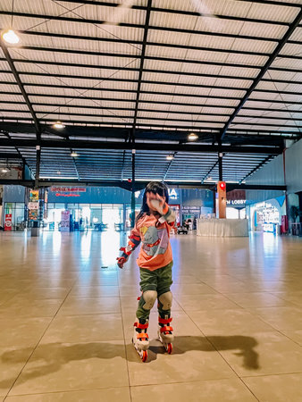 An energetic young child, wearing roller skates and knee pads, practices her skills in a spacious...