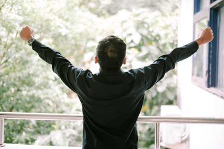 A man stands with his back to the viewer, arms outstretched wide, enjoying the fresh air and view...