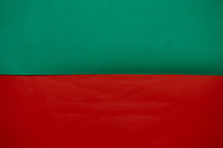 A vibrant and colorful abstract background featuring a clear horizontal split between bright green and bold red textured paper.の写真素材
