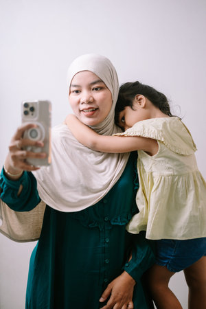 An affectionate Muslim mother and her young daughter are enjoying a heartwarming moment, taking a...