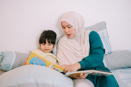 A young Muslim mother and daughter enjoying a picture book together, highlighting family affection and childhood education.の写真素材