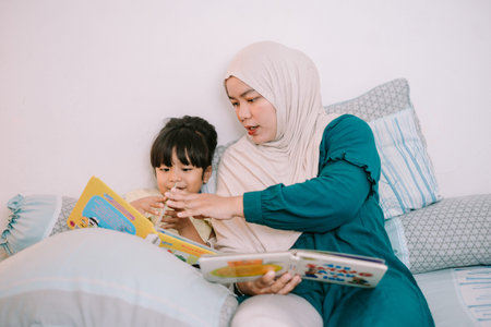 Tender moment of a Muslim mother reading with her daughter, creating a calm environment for storytelling and learningの写真素材