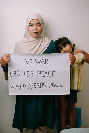 A Muslim mother and her daughter stand together, holding a powerful handmade sign advocating for...