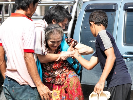 October 21, 2011 Rongsit Road, Phathumtrani, Thailand: Rescue  helping sick woman through the water during the worst flooding in decades のeditorial素材