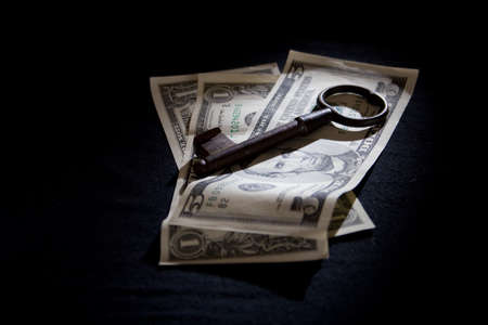 An old key on US dollar notes. positioned in a spotlight.の写真素材