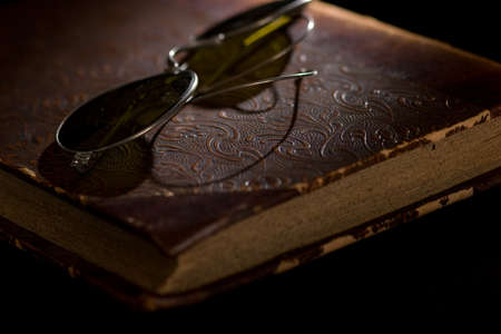 An old worn accounting book and glasses ontop.の写真素材