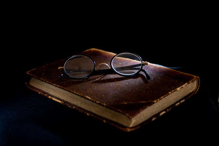 An old worn accounting book and glasses ontop.の写真素材