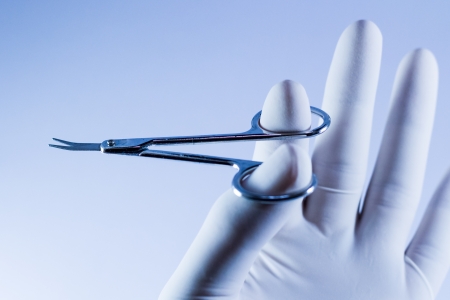 Hand with white glove holding the scissors.の写真素材