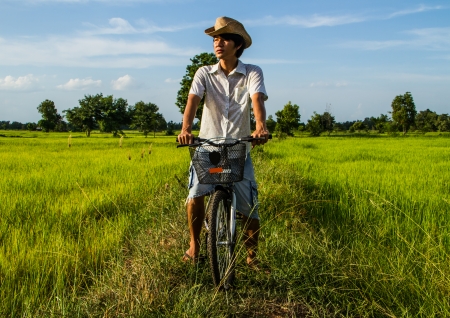 Farmer riding bicycle in the rice field.の写真素材