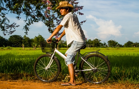 Farmer riding bicycle in the rice field.の写真素材