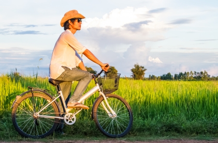 Farmer riding bicycle in the rice field.の写真素材