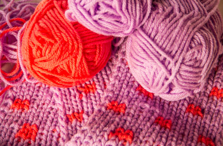 Purple and red wools knitting close up pattern and materials.