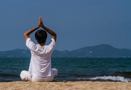 Asian man having yoga at the beach.の写真素材