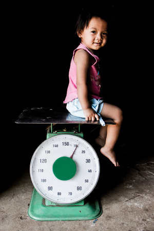 Asian girl sitting on scales.の写真素材