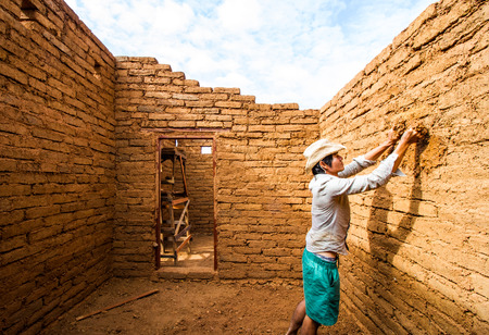 Builder plastering wall in earthen house.の写真素材