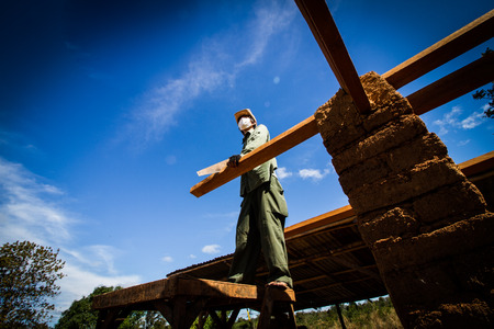 Builder sawing wooden roof for earthen house.の写真素材
