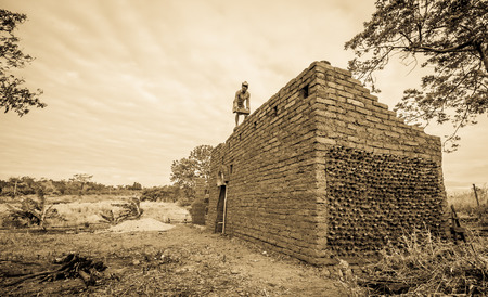 Builder building earthen house on top of the wall.の写真素材