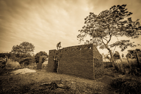 Builder building earthen house on top of the wall.の写真素材