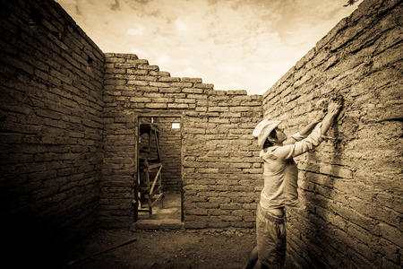 Builder plastering wall in earthen house.の写真素材