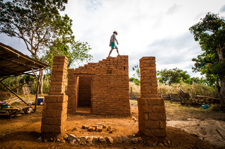 Builder walking on earthen house while building.の写真素材