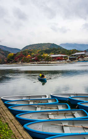 KYOTO,JAPAN - NOVEMBER 25, 2019: Tourist rowing a boat to enjoy the autumn view with maple trees along the bank of Katsura river in Arashiyama, Kyoto, Japan.Arashiyama is one of tourist destination in Kyoto.のeditorial素材