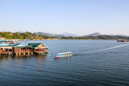 Boat goint pass houseboat to the land.の写真素材