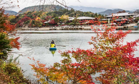 KYOTO,JAPAN - NOVEMBER 25, 2019: Tourist rowing a boat to enjoy the autumn view with maple trees along the bank of Katsura river in Arashiyama, Kyoto, Japan.Arashiyama is one of tourist destination in Kyoto.のeditorial素材