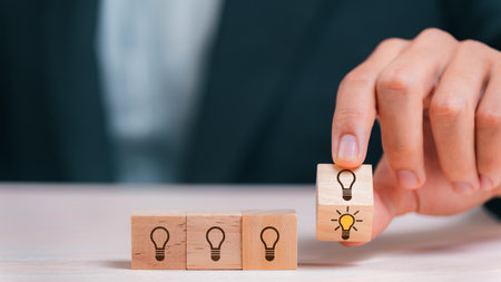 Leader choosing the best new idea with light bulb icon on wooden blocks. Explore creative design, solutions, strategy reviews. Inspiring innovation and teamwork.の写真素材