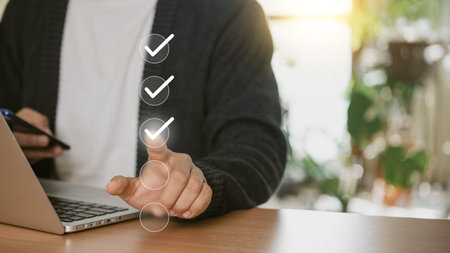 A businessman uses his laptop at home to select the appropriate box for quality document control,...