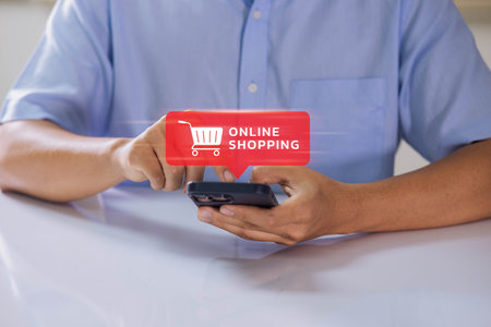 The idea of e-commerce or internet buying. A businessman uses a smartphone to peruse an online shopping basket. He buys and sells services across a network using global technology and the internet.の写真素材