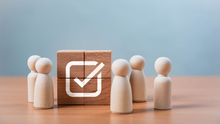 Teamwork and Business Success. A group of happy wooden figures surrounds a wooden disc with a checkmark, representing teamwork, success, quality assurance, leadership, and positive evaluation.の写真素材