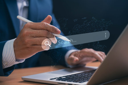 Concept of global search. Businessman with search bar on laptop, representing global digital research, data analysis, innovation trends, and online information exploration for strategic planning.の写真素材