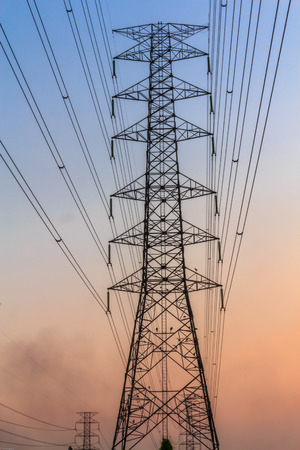 Electric power lines against blue and yellow skyの写真素材