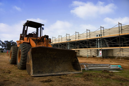 Earth mover in front of scaffolding for a new parking lot under construction