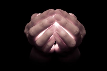 Hands holding a glowing candle, with light pouring through the fingers that appear translucent.  Muted tones.の写真素材